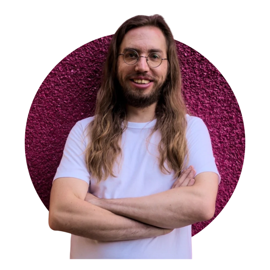 A photo of Jake Vanderwerf with his arms crossed in front of a pink, textured wall